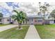 Charming home with a well-manicured lawn, a palm tree, and a welcoming walkway leading to the front door at 1142 56Th N Ave, St Petersburg, FL 33703
