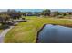 Aerial view of The Eagles golf course with a pond and the clubhouse in the background at 12707 Green Heron Way, Odessa, FL 33556