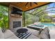Covered outdoor fireplace and seating area with a pool view provide a cozy spot for relaxation and entertaining at 12707 Green Heron Way, Odessa, FL 33556