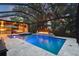 View of the screened-in in-ground pool with outdoor kitchen and fire pit at dusk at 12707 Green Heron Way, Odessa, FL 33556