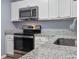 Modern kitchen features granite counters, stainless steel appliances, and white cabinets at 14734 11Th St, Dade City, FL 33523