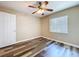 A bedroom with wood-look floors, ceiling fan, and a door and window, is a blank canvas at 1535 Nursery Rd # 107, Clearwater, FL 33756