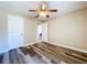 This bedroom has wood-look floors, a ceiling fan, and neutral walls and is connected to another room at 1535 Nursery Rd # 107, Clearwater, FL 33756