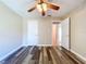 Bedroom with ceiling fan, wood floors, and an open doorway to other parts of the house at 1535 Nursery Rd # 107, Clearwater, FL 33756