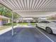 View of a white sedan parked in a carport with a view of condos with pink shutters at 1535 Nursery Rd # 107, Clearwater, FL 33756