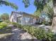 Exterior view of a condo building featuring well-maintained landscaping, pink shutters, and a concrete patio at 1535 Nursery Rd # 107, Clearwater, FL 33756