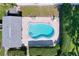 Aerial shot of a blue kidney-shaped pool with patio, lounge chairs, privacy hedges, and a storage building at 1535 Nursery Rd # 107, Clearwater, FL 33756