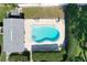Aerial shot of a blue kidney-shaped pool with patio, lounge chairs, privacy hedges, and a storage building at 1535 Nursery Rd # 107, Clearwater, FL 33756