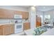 Kitchen with wood cabinets, white appliances, and views into the dining area at 16501 Sandhill Crane Dr, Spring Hill, FL 34610
