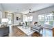 Open-concept living room with hardwood floors and neutral furniture, showcasing access to the entryway and outdoor views at 16501 Sandhill Crane Dr, Spring Hill, FL 34610