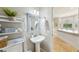 Cozy half bathroom with a pedestal sink, decorative mirror, shelving, and adjacent views into the dining area at 17712 Long Ridge Rd, Tampa, FL 33647