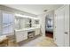 Bright bathroom with double vanity, large mirror, and an adjacent bedroom with a view to the closet at 17712 Long Ridge Rd, Tampa, FL 33647