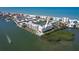 Stunning aerial view of a beachfront condo complex with a pool, tennis courts, and boat docks, situated between the ocean and bay at 19451 Gulf Blvd # 506, Indian Shores, FL 33785