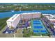 Expansive aerial view showcases the waterfront condo with tennis courts, parking, and lush landscaping in a desirable location at 19451 Gulf Blvd # 506, Indian Shores, FL 33785