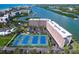 Stunning aerial view of a condo community featuring tennis courts, water access, and immaculate landscaping at 19451 Gulf Blvd # 506, Indian Shores, FL 33785