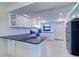 Modern kitchen with white cabinets, black countertop, stainless steel appliances, and sleek gray flooring at 19451 Gulf Blvd # 506, Indian Shores, FL 33785