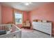 Bright Bedroom with white crib, round pink rug, gray walls, and curtains at 20472 Monza Loop, Land O Lakes, FL 34638