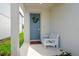 Welcoming front porch features a blue door, wreath, a white bench, and a welcome mat at 20472 Monza Loop, Land O Lakes, FL 34638