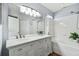 Bright bathroom featuring double sinks, a large mirror, and a shower over the tub at 24231 Satinwood Ct, Lutz, FL 33559