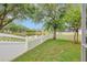 Lush backyard with a white fence and a scenic view of the pond and mature trees at 3510 Hickory Hammock Loop, Wesley Chapel, FL 33544