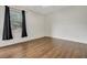 This empty bedroom has wood floors and a window with dark curtains at 3510 Hickory Hammock Loop, Wesley Chapel, FL 33544