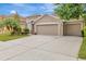 Spacious driveway leading to a tan home with a two-car garage and lush landscaping at 3510 Hickory Hammock Loop, Wesley Chapel, FL 33544
