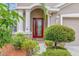 Inviting front entrance with a red glass door, flanked by columns and lush greenery at 3510 Hickory Hammock Loop, Wesley Chapel, FL 33544