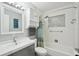 Well-lit bathroom with white tiled shower-tub combo, gray vanity and stylish medicine cabinet with louvred doors at 511 Glenoak N St, St Petersburg, FL 33703
