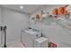 Well-lit laundry room with washer, dryer, and storage shelves at 5922 Grand Sonata Ave, Lutz, FL 33558