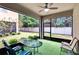 Enclosed porch featuring green turf, seating, ceiling fan, and views of the backyard at 5922 Grand Sonata Ave, Lutz, FL 33558