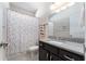 Bright bathroom with a colorful shower curtain and dark vanity with granite countertop at 6015 Shell Ridge Dr, Lithia, FL 33547