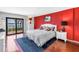 Bright main bedroom featuring a red accent wall, white furniture, and a sliding glass door to balcony with beautiful views at 650 Island Way # 204, Clearwater Beach, FL 33767