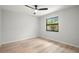 Bright bedroom features light wood floors, ceiling fan, and a window with wooded view at 1047 Deer Hollow Way, Sarasota, FL 34232