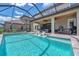 A large swimming pool with a screened-in enclosure and a seating area with a grill at 11227 Hawks Fern Dr, Riverview, FL 33569