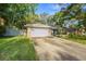 Quaint one-story home with stone detailing and a spacious driveway, surrounded by lush green grass and a light-colored fence at 14 Idlewilde Dr, Safety Harbor, FL 34695