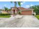 Inviting single-story home featuring a landscaped front yard, arched windows, and a two-car garage at 18005 Palm Breeze Dr, Tampa, FL 33647