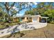 Charming, one-story yellow home with a driveway and carport nestled under large, shady trees at 2049 Broadway, Clearwater, FL 33755