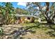 Charming yellow single-story home with lush landscaping and mature trees in the front yard at 2049 Broadway, Clearwater, FL 33755
