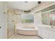 Bright bathroom featuring a large soaking tub, glass block window, and a separate glass shower with gold trim at 26180 Deep Creek Blvd, Punta Gorda, FL 33983
