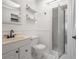 Bright bathroom features a toilet, cream vanity, glass enclosed shower, and a wall mirror with decorative shelves at 3212 W Arch St, Tampa, FL 33607