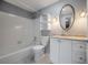 Updated bathroom with white tiled shower/tub, vanity, and an oval decorative mirror at 3212 W Arch St, Tampa, FL 33607