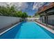 Inviting in-ground pool, secured by a safety fence, with an adjacent wooden deck and string lights overhead at 3212 W Arch St, Tampa, FL 33607