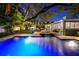 Beautiful backyard oasis featuring a sparkling pool, lush landscaping, cozy seating areas, and festive lighting for an inviting ambiance at 3505 W Kensington Ave, Tampa, FL 33629