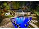 Expansive backyard featuring a brilliant pool, poolside lounge, and lush landscaping, all illuminated for a stunning evening ambiance at 3505 W Kensington Ave, Tampa, FL 33629