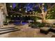 Stunning outdoor space with a sparkling pool, lounge chairs, cozy seating, and lush landscaping under festive string lights at 3505 W Kensington Ave, Tampa, FL 33629