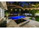 An inviting pool area with adjacent spa and manicured landscaping are illuminated by romantic string lights at 3505 W Kensington Ave, Tampa, FL 33629