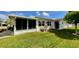 A beautifully maintained lawn leads up to a white home featuring a screened-in porch and large windows at 3890 Mainlands N Blvd, Pinellas Park, FL 33782