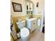 Traditional bathroom with a white sink, vanity, and toilet, complemented by yellow tiling and a charming wall cabinet at 3890 Mainlands N Blvd, Pinellas Park, FL 33782