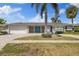 Inviting home featuring a well-manicured lawn, brick driveway, palm trees, and a bright blue double door at 3910 Doral Dr, Tampa, FL 33634
