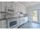 Bright kitchen featuring white cabinets, modern appliances, and granite countertops with gray wood floor at 4001 W North A St, Tampa, FL 33609